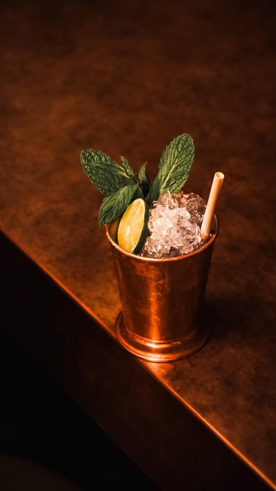 Bakır julep bardağında kırılmış buz, taze nane demeti ve lime dilimi, jain bambu pipet ile